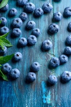 Fresh blueberries on blue rustic wooden table pattern. Healthy organic seasonal fruit background design. Organic food blueberries and mint leaf for healthy lifestyle.