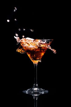 Martini cocktail splash over black background. Cocktail happy hour and night club party concept.