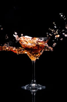 Martini cocktail splash over black background. Cocktail happy hour and night club party concept.
