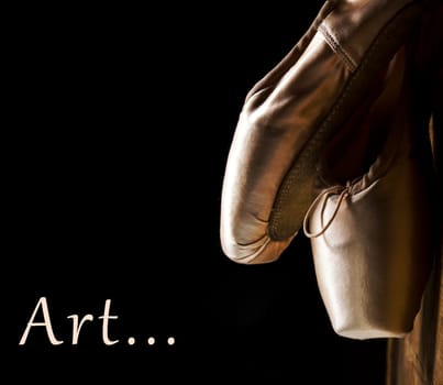 Ballet pointe shoes hanging over black background. Art concept still life. Classical ballet dance items and accessory.