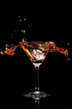 Martini cocktail splash over black background. Cocktail happy hour and night club party concept.