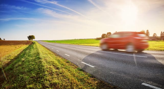 Car moving on the coutry road in sunset. Background of the rural scene in natural park.
