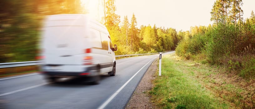 Van moving on the country road in natural park on the sunset. Concept of import and export.