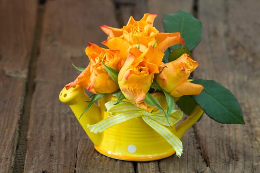 orange roses in a vase on wooden background
