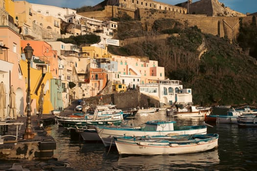 View of the Port of Corricella with lots of colorful houses on a sunny day in Procida Island, Italy.