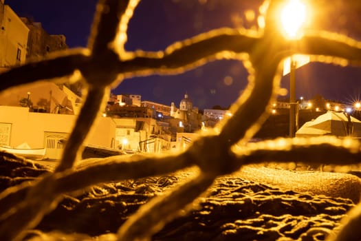 Fishing nets the Port of Corricella with lots of colorful houses after sunset in Procida Island, Italy.