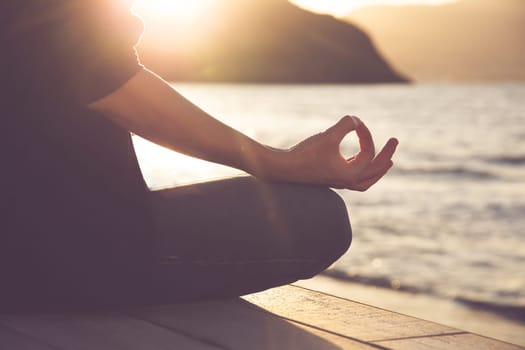 Woman in a yoga pose at sunset at the beach. Mindfulness and mental health concept.