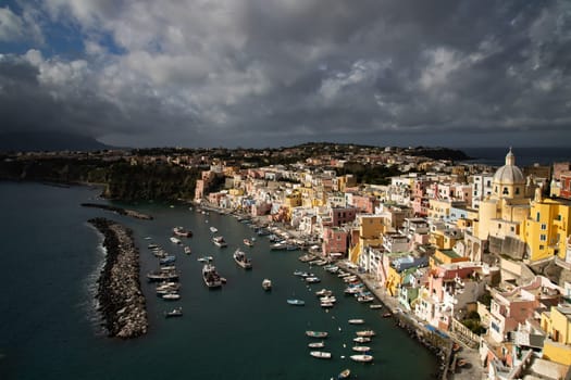 View of the Port of Corricella with lots of colorful houses on a sunny day in Procida Island, Italy.