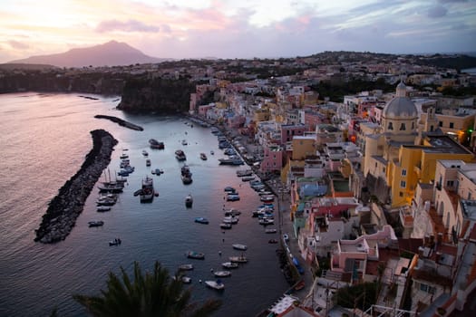 View of the Port of Corricella with lots of colorful houses in the sunset, Procida Island, Italy.