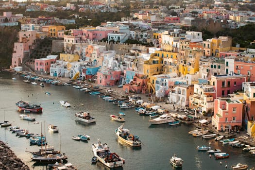 View of the Port of Corricella with lots of colorful houses in the sunset, Procida Island, Italy.