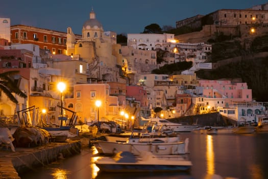View of the Port of Corricella with lots of colorful houses at night in Procida Island, Italy.