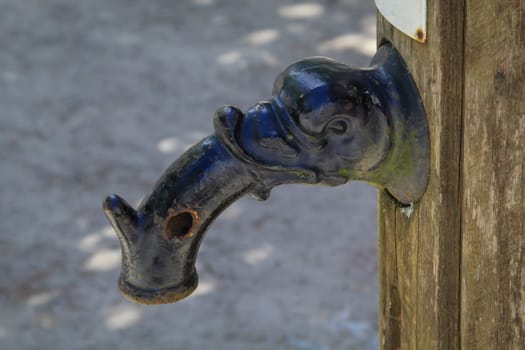 The cast iron spout of an old large swing pump.