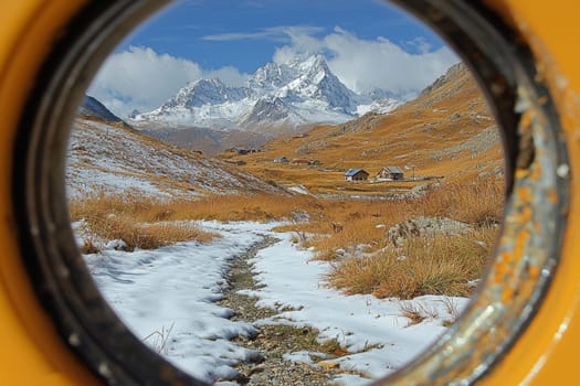 Glimpse of snow-dusted peaks and rustic homes from a circular viewpoint, showcasing nature's beauty and seasonal transition.