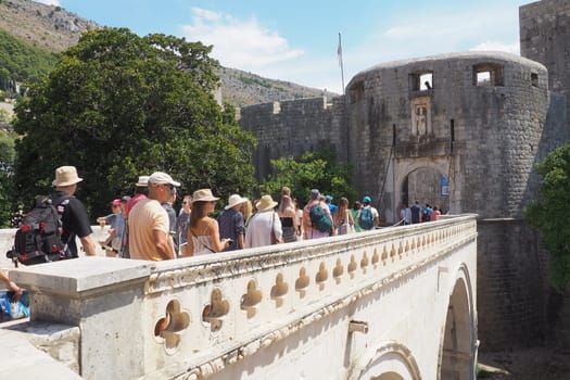 Pile Gate Dubrovnik Croatia August 14 2022 People men and women walk along the stone bridge to the gate of the Old City. Crowd of tourists. Busy entrance. The main entrance to Old Town, busy Pile Gate