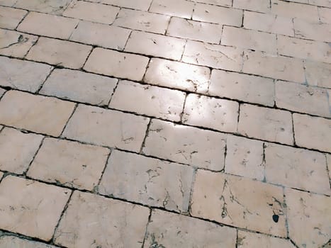 Marble floor on the street, Dubrovnik, Croatia. Antique masonry tiles rectangular blocks. Metamorphic rock composed of calcite CaCO3 mixed with other minerals. Polished tiles glisten in the sun.