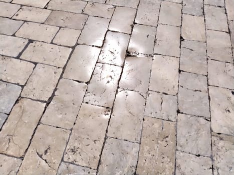 Marble floor on the street, Dubrovnik, Croatia. Antique masonry tiles rectangular blocks. Metamorphic rock composed of calcite CaCO3 mixed with other minerals. Polished tiles glisten in the sun.