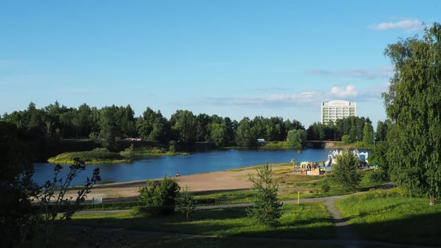 Mouth, floodplain and terraces of the Lososinka River, Petrozavodsk, Republic of Karelia August 3, 2022. Sunny windless evening. City sandy beach. Passers-by people with children walk. Hotel Karelia.