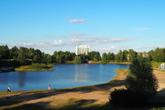 Mouth, floodplain and terraces of the Lososinka River, Petrozavodsk, Republic of Karelia August 3, 2022. Sunny windless evening. City sandy beach. Passers-by people with children walk. Hotel Karelia.