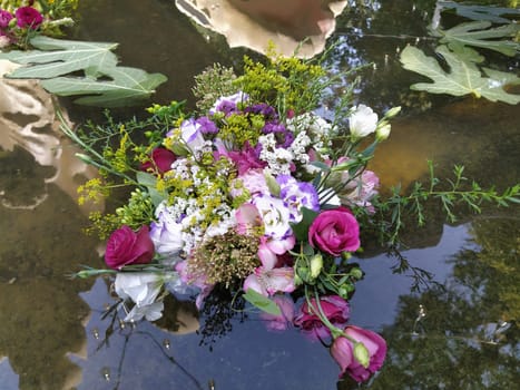 pink and red roses in a bouquet floating in the water of a fountain. Plucked buds as decoration for a summer holiday. Ivan Kupala, summer solstice. Harvest festival