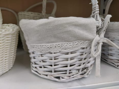 Wicker decorative baskets on a shelf in a store. Pretty baskets painted white. Textile bag. Stylish gift for Easter. Decor element of the interior of an apartment, a country house or a spring garden