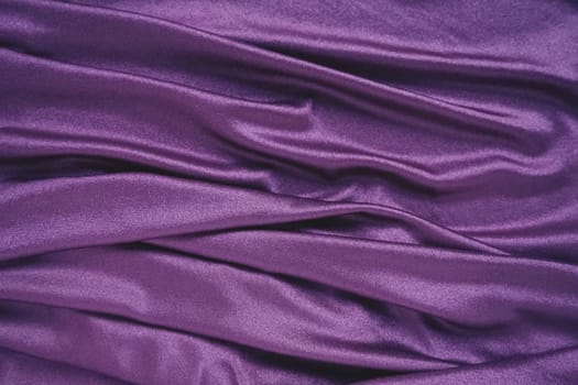 Velour fabric, similar to silk. Textiles in a folds and beautiful waves. Purple, pink, magenta shades on the drapery. Sewing material for evening dresses, furniture upholstery, curtains and interior