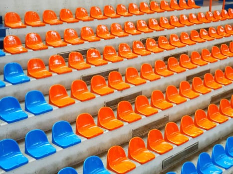 Bleachers, empty seats in the stands of the arena or auditorium. Rows of blue and orange stadium seats without spectators. The concept of the abolition of sports and mass entertainment events.