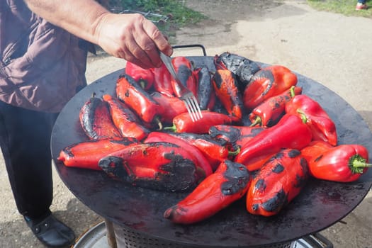 Roasting red peppers for a smoky flavor and quick peeling. Thermal processing of the pepper crop on metal circle. Brazier container used to burn charcoal fuel for cooking, heating or cultural rituals