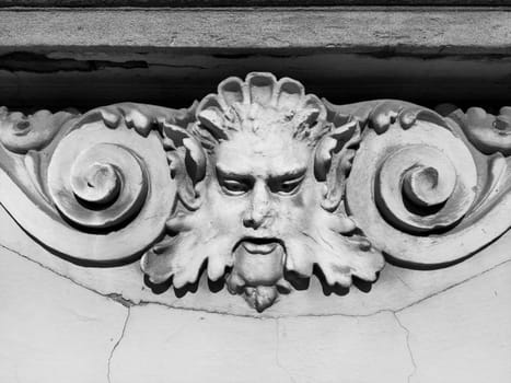 Decorative detail on the facade. Relief on the facade of a building. Stucco molding in the form of a man's head with curly hair, mustache and curls on the sides. High relief concrete bas-relief