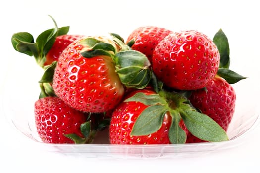 Ripe strawberries in a plastic package on a white background. Delicious fresh berries in a container for sale to customers. Keeping food fresh. Healthy food, vitamins and microelements