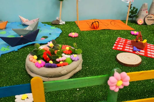 Easter composition made by children at school in the labor lesson. Village yard, eggs in a basket, green artificial grass. Painted fence. Application and sculpture in children's creativity