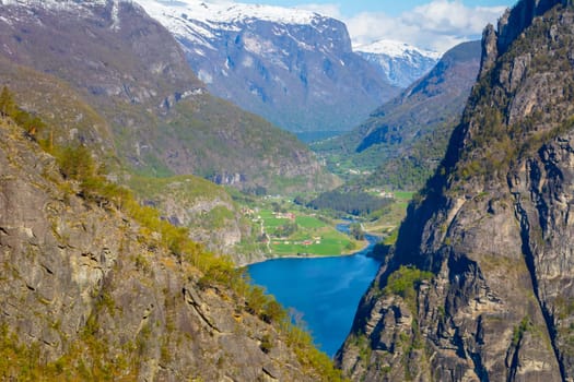 View on Norwegian fjord village in the distance, looking through rocks and mountains. Travel and tourism in Norway.