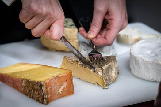 a waiter is cuting a cheese for his client in a hotel