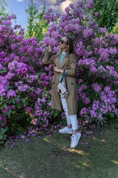 A woman smells purple flowers on a rhododendron bush
