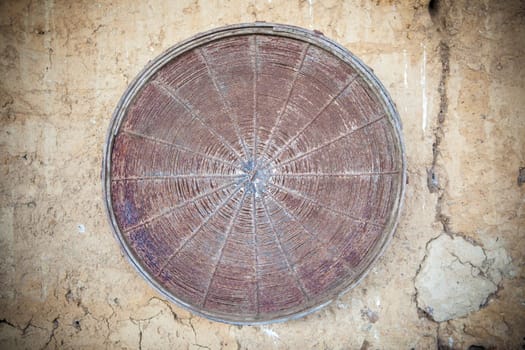 Old rusty sieve attacched over barn adobe wall. Selective focus