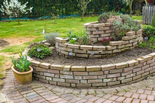 herb spiral in the garden with herbs and flowers