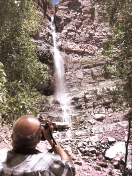 A man photographing Cascade Falls in Ouray, Colorado.