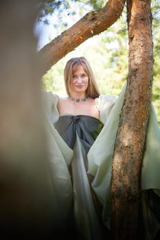 Beautiful dryad or fairy near trees. Pagan spirit of forest. Environmental friendliness, caring for nature. Adult mature woman 40-60 in Photo shoot