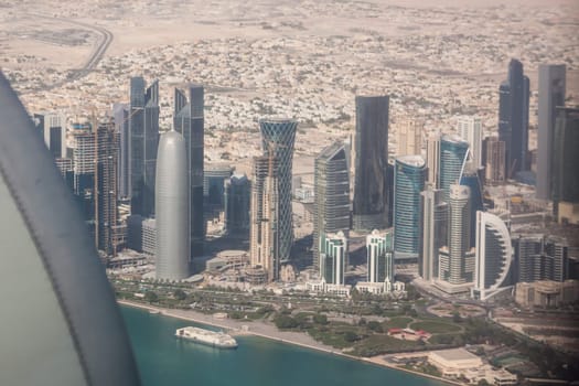 Aerial view of Doha through plane window, capital of Qatar in the Persian Gulf