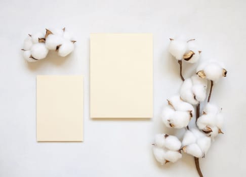 Blank cards with cotton flowers top view on white, mockup. Romantic scene with wedding suite. Bohemian pastel vertical greeting or wedding set