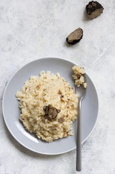 Risotto with wild porcini mushrooms and black truffles from Italy served in a plate top view on white table, copy space. Eating Italian gourmet cousine
