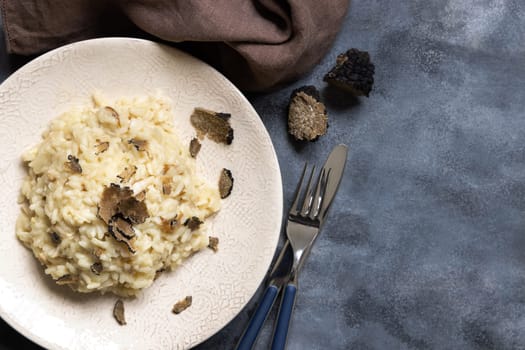 Risotto with wild porcini mushrooms and black truffles from Italy served in a plate top view on grey table, copy space. Eating Italian gourmet cousine