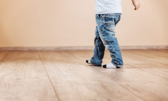 Child walking along the living room. Concept of the new house and control warming in the house.