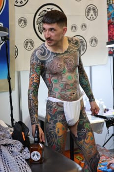 Krakow, Poland -  June 11, 2022: Unidentified  participant at 15th Tattoofest Convention in Cracow. One of the most prestigious tattoo festivals. Tattoo artist at work.