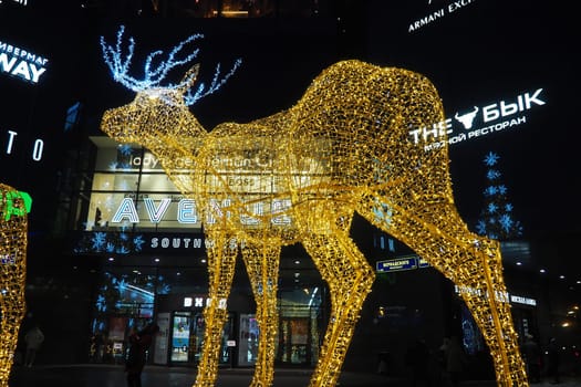 Moscow, Russia, January 17 2023 Metro Yugo-Zapadnaya. Christmas decorations in front of the mall. New year street decorations in the form of sparkling deer. Deer figure made from yellow gold garlands
