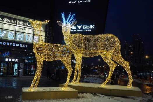 Moscow, Russia, January 17 2023 Metro Yugo-Zapadnaya. Christmas decorations in front of the mall. New year street decorations in the form of sparkling deer. Deer figure made from yellow gold garlands