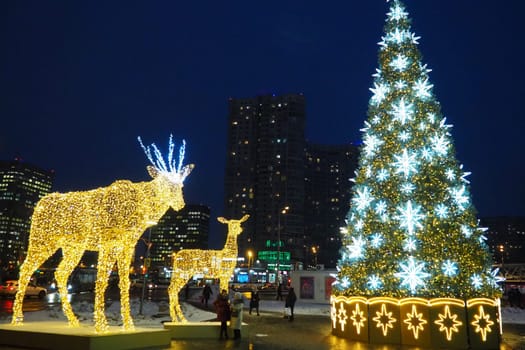 Moscow, Russia, January 17 2023 Street Christmas tree with snowflakes and festive balls. Metro Yugo-Zapadnaya. Christmas decorations in front of the mall. Silver stars, snowflakes and golden deers.