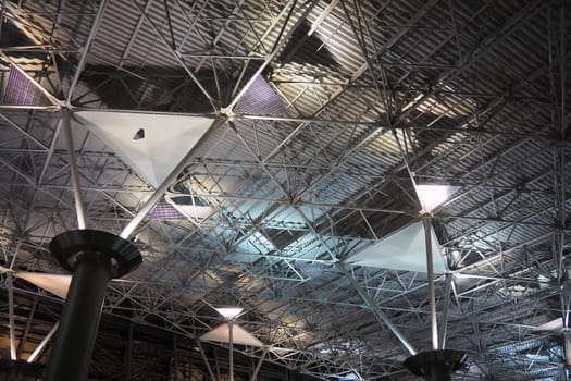 Metal structures under the ceiling. Decorative details of the airport ceiling . Concrete beams, glass windows and metal elements as public building interior design. Abstract avant-garde architecture