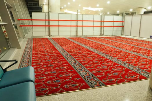 Ankara, Turkiye, Esenboga Havalimani Airport, 01.18.2023 Empty prayer hall at night. Namaz or salat is a prayer in Islam. Isha prayer. Red prayer carpet. Nobody at night. Sajjada, namazlik, jai-namaz.