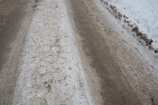 Snowdrifts on the side of the road. Bad weather and traffic. Snow on asphalt. Difficult driving conditions. Winter slush on the road. Wet weather, freezing temperatures. Weather forecast ice and snow.