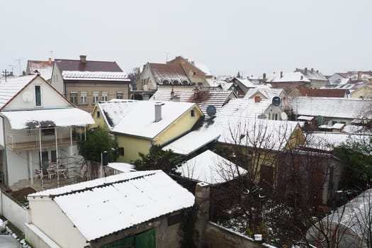 Sremska Mitrovica, Serbia, 01.27.2023 Snowfall in the city. Roofs of houses covered with snow. Weather forecast. Cloudy winter day. City landscape. Stove heating with coal and wood. Economic crisis